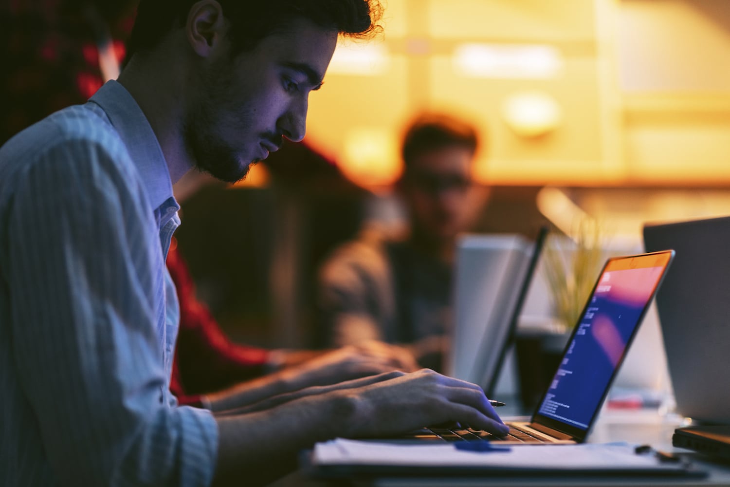 A developer working at a laptop in a warmly lit office