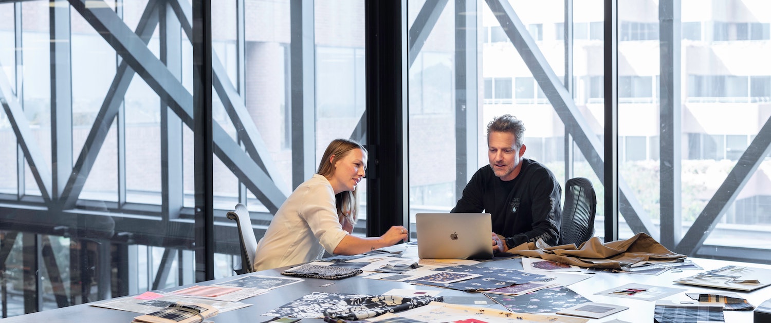 Two colleagues discussing a website project on a sofa in a bright studio